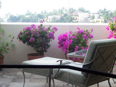 a chair and ottoman on a balcony with purple flowers