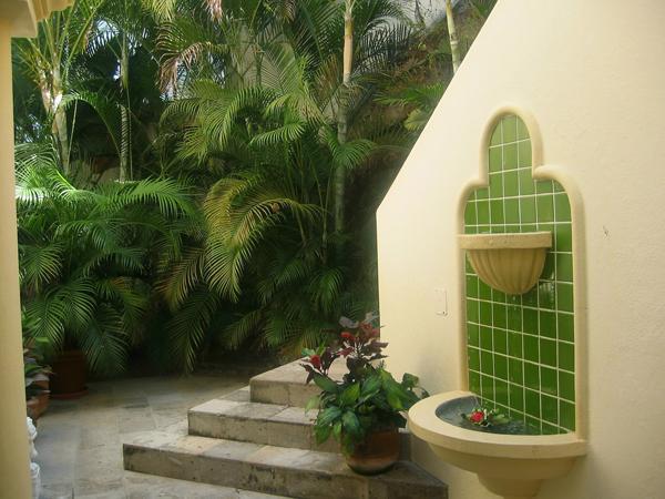 a potted plant sits next to a fountain in a garden .