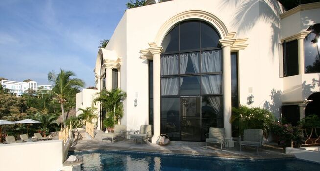 back of a large white villa with a swimming pool