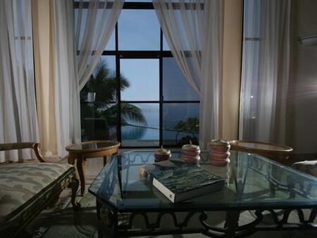 a living room with a glass coffee table and a large window with a view of the ocean .