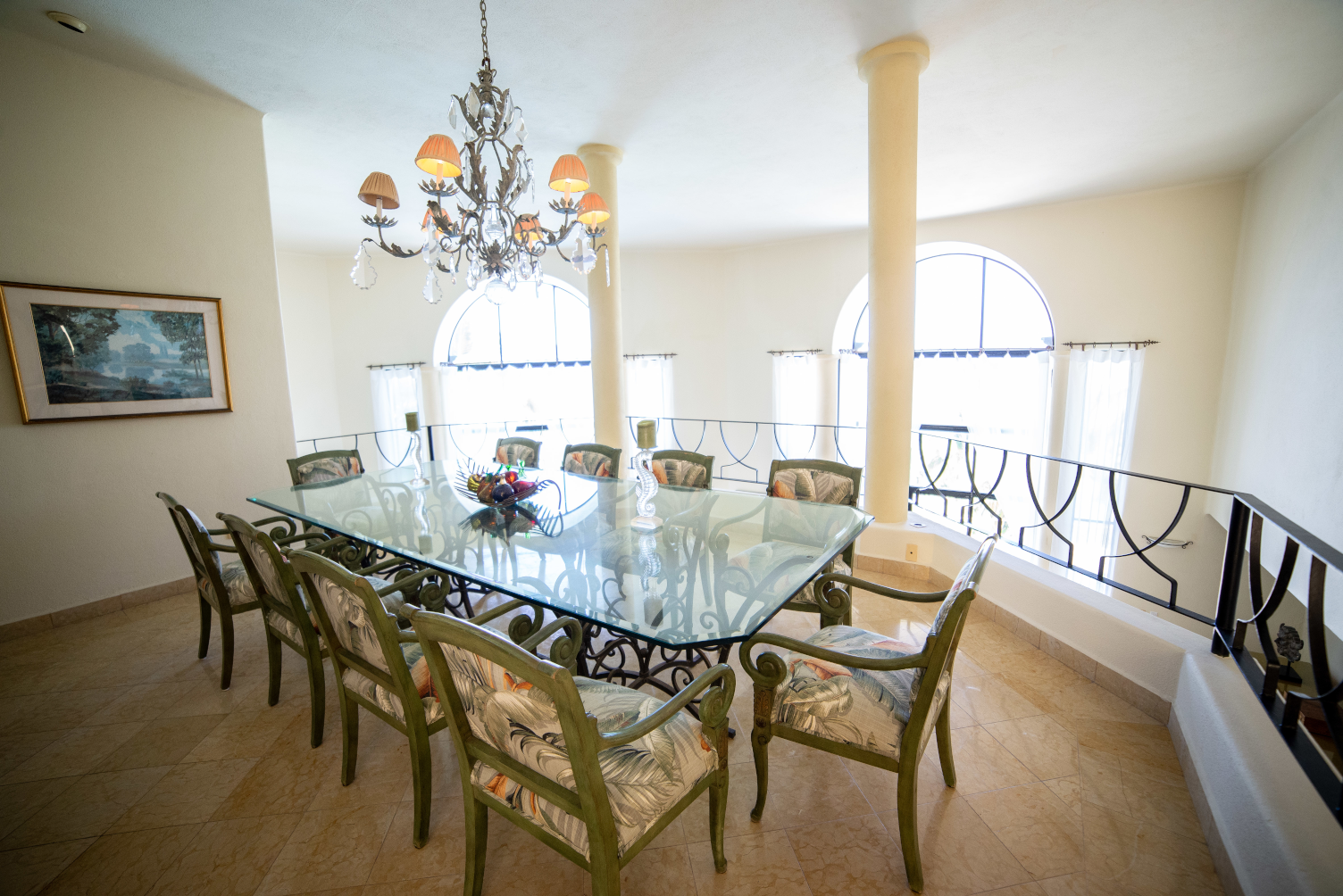 A dining room with a glass table and chairs and a chandelier.