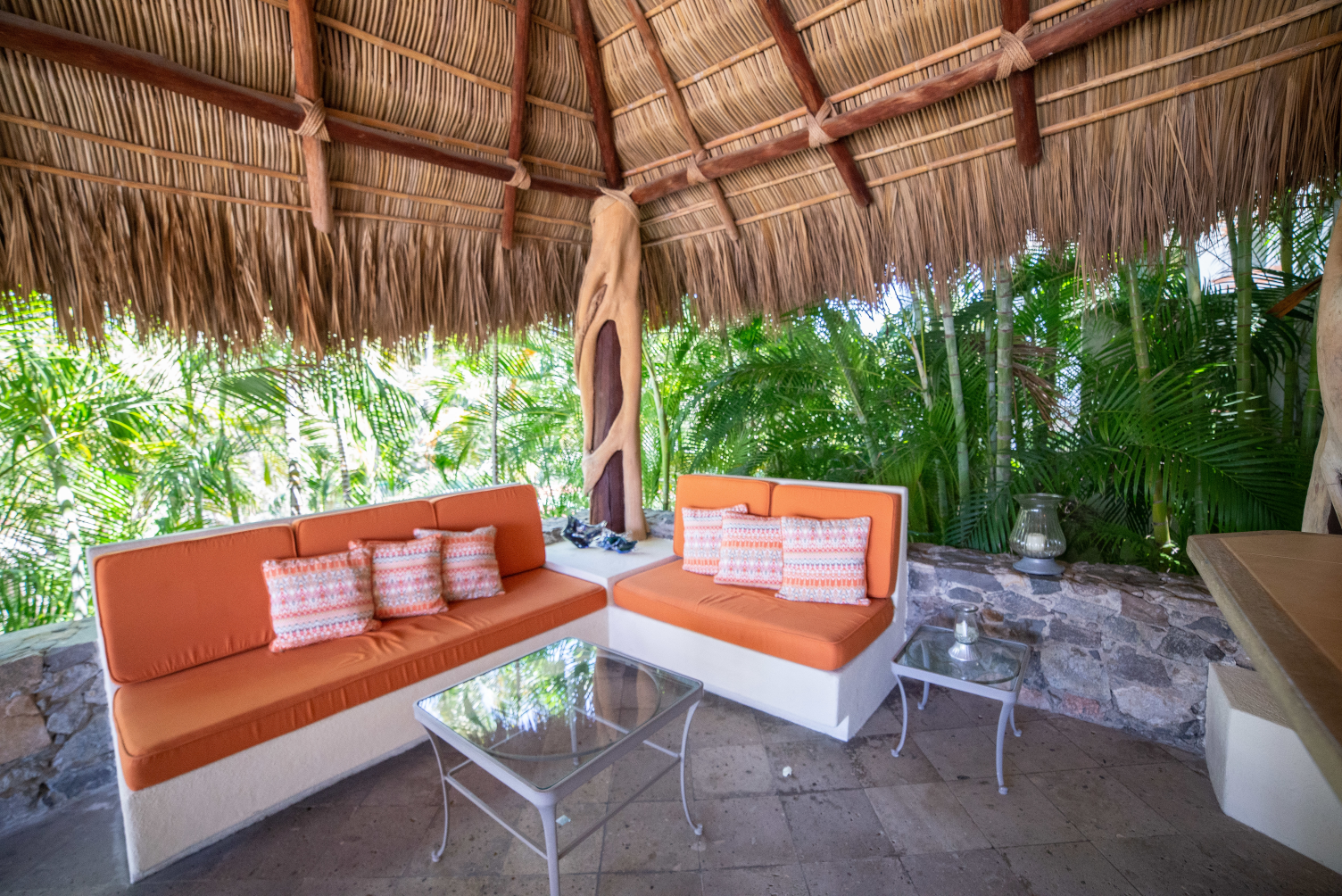an outdoor living space with orange couches and a thatched roof .
