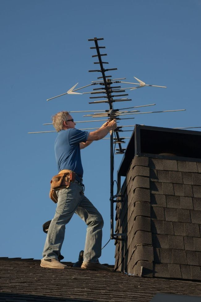 A Man Is Standing on A Roof Fixing an Antenna — T.N. Locke Communications In Kirwan, QLD