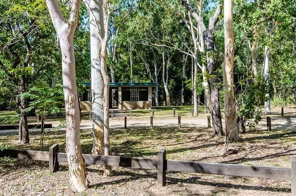 A Wooden Fence Surrounds a House in The Middle of A Forest — T.N. Locke Communications In Alligator Creek, QLD