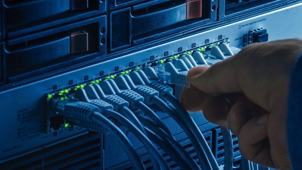 A Person Is Plugging a Cable Into a Server — T.N. Locke Communications In Kirwan, QLD