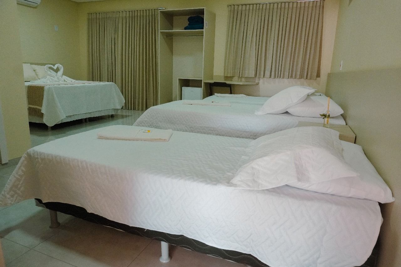 Um quarto de hotel com três camas e uma escrivaninha.