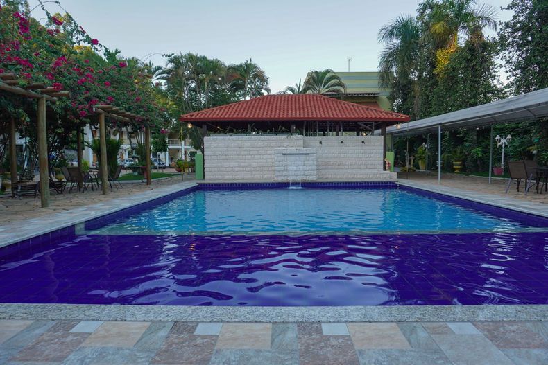 Uma grande piscina rodeada de árvores e um edifício com telhado vermelho.