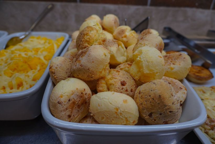 Uma tigela de bolinhos de queijo está sobre uma mesa ao lado de uma tigela de macarrão com queijo.