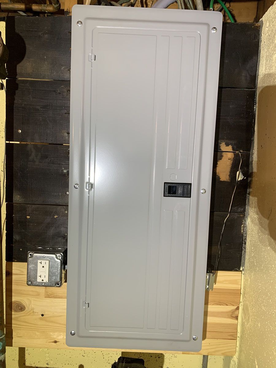 Gray electrical panel on a wooden surface with an outlet.