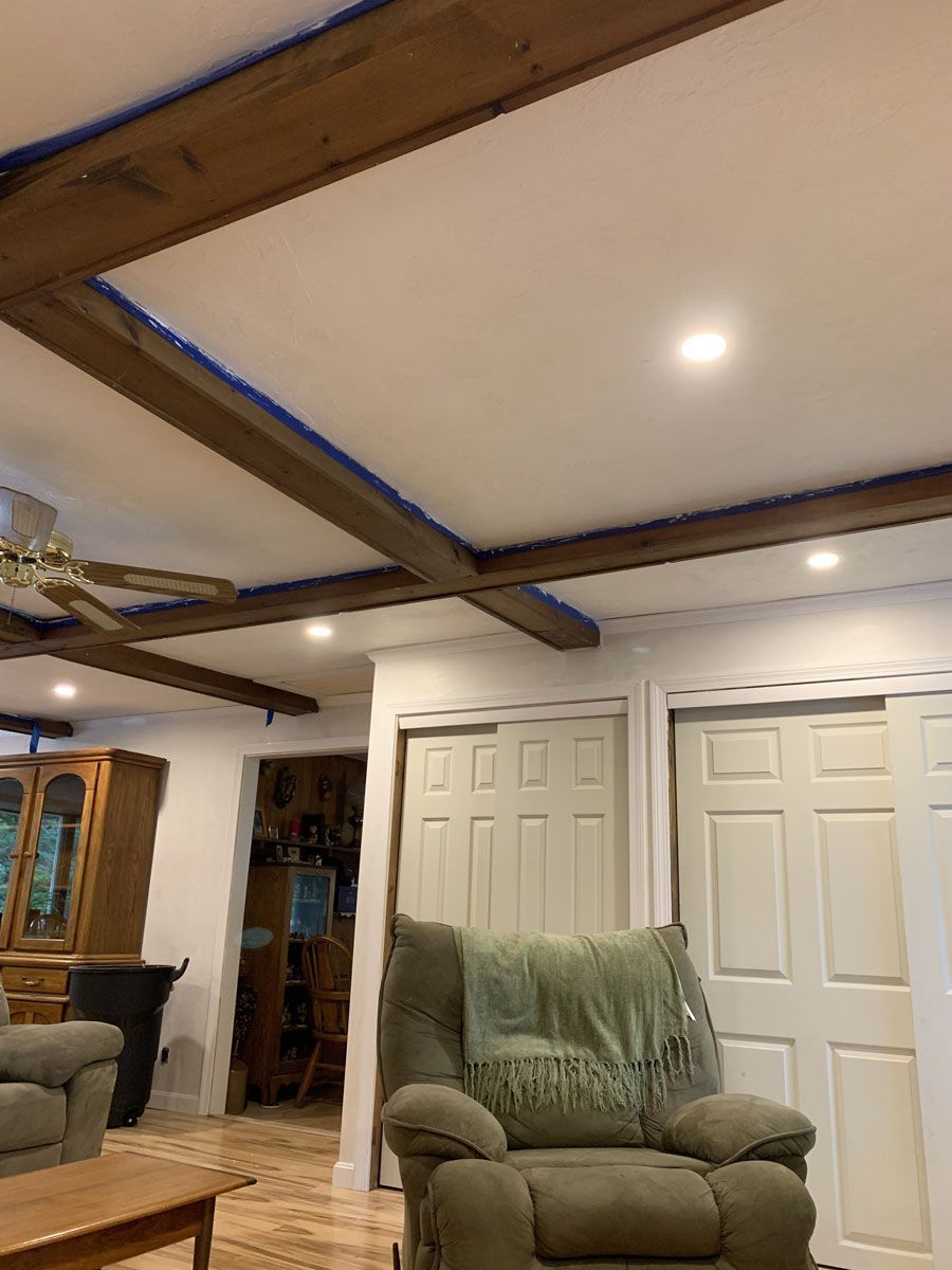 Living room with wood beams on a white ceiling, two white sliding closet doors, and a recliner chair.