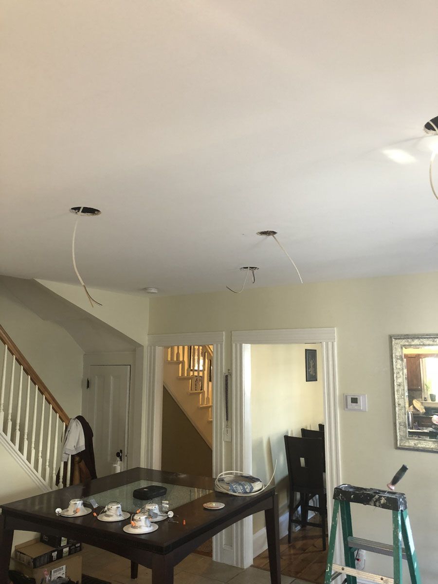 Dining room ceiling with three pendant light fixtures and exposed wiring; table, staircase, doorway.