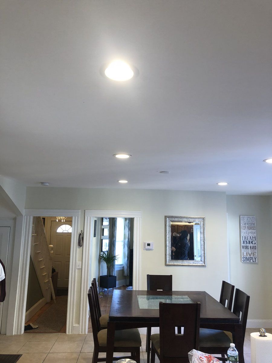 Dining room with dark wooden table, chairs, and overhead lighting. Hallway and mirror visible.