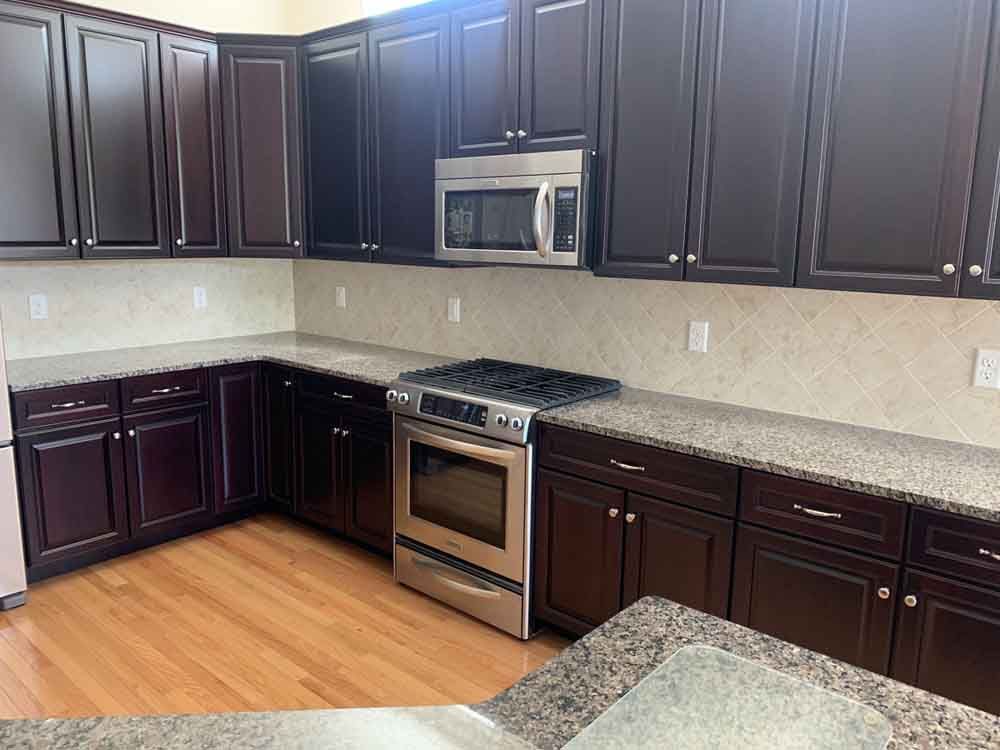 Dark wood kitchen cabinets with stainless steel appliances and granite countertops.
