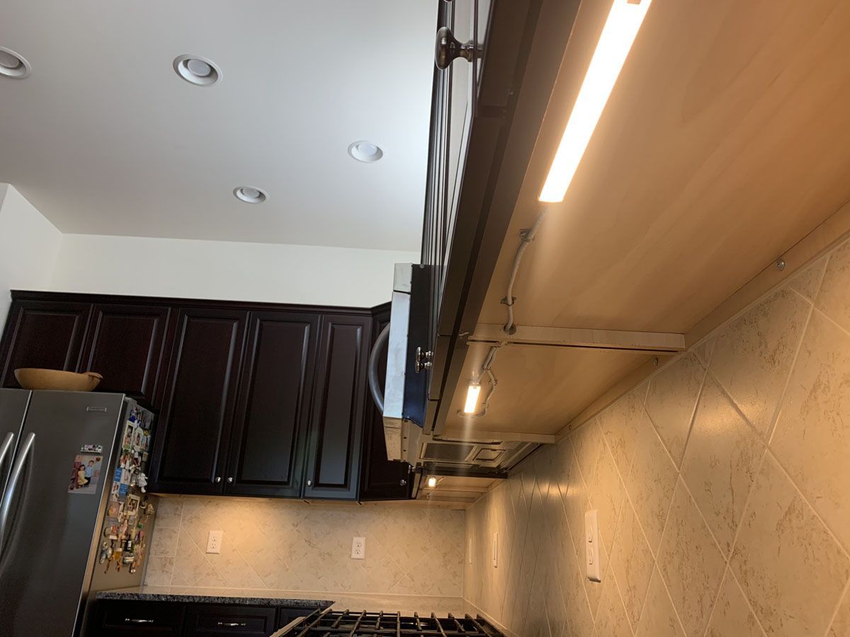 Kitchen with dark cabinets, stainless steel range hood, and under-cabinet lighting.