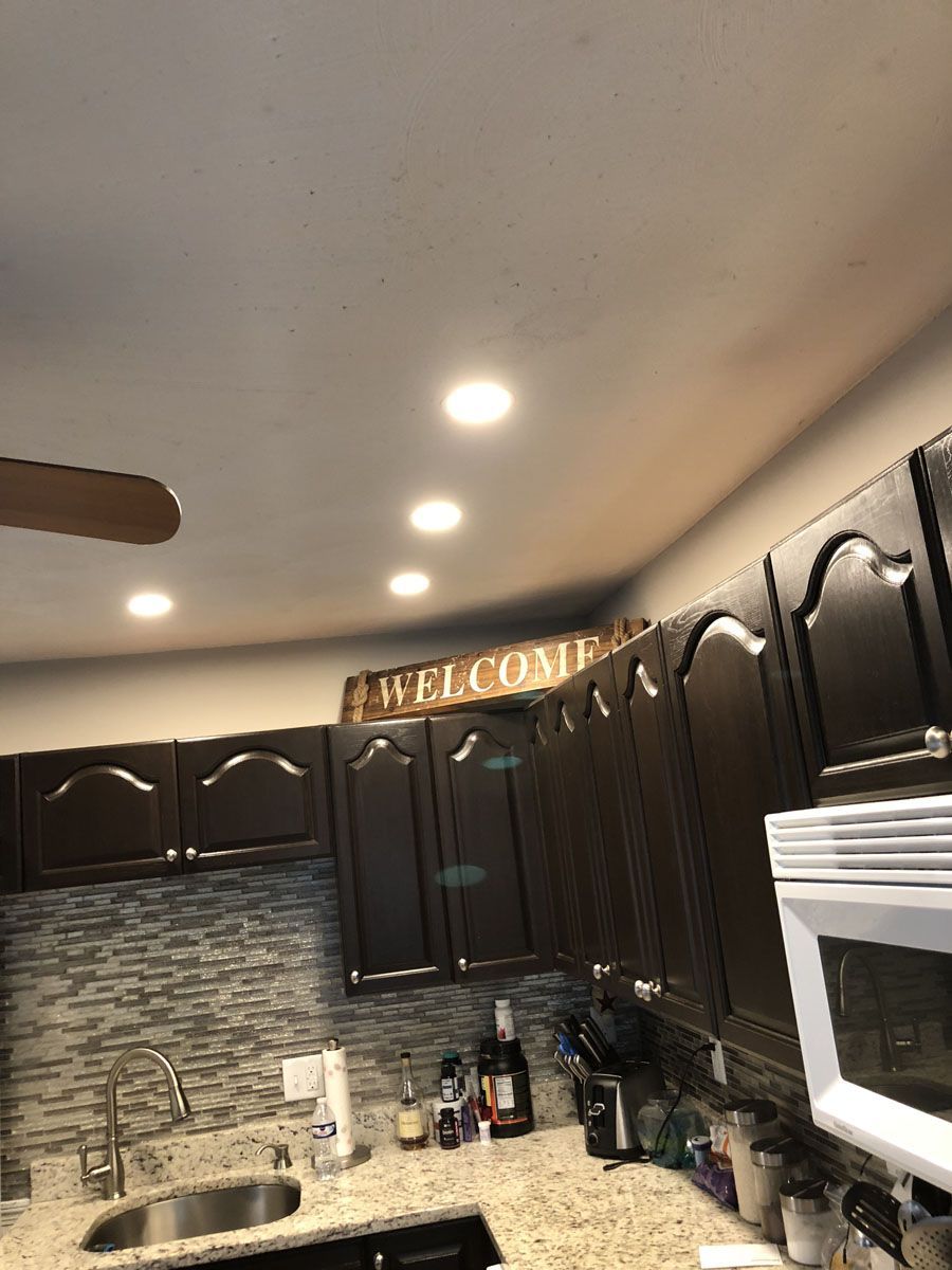 Kitchen with dark brown cabinets, silver sink, and recessed ceiling lights. A 
