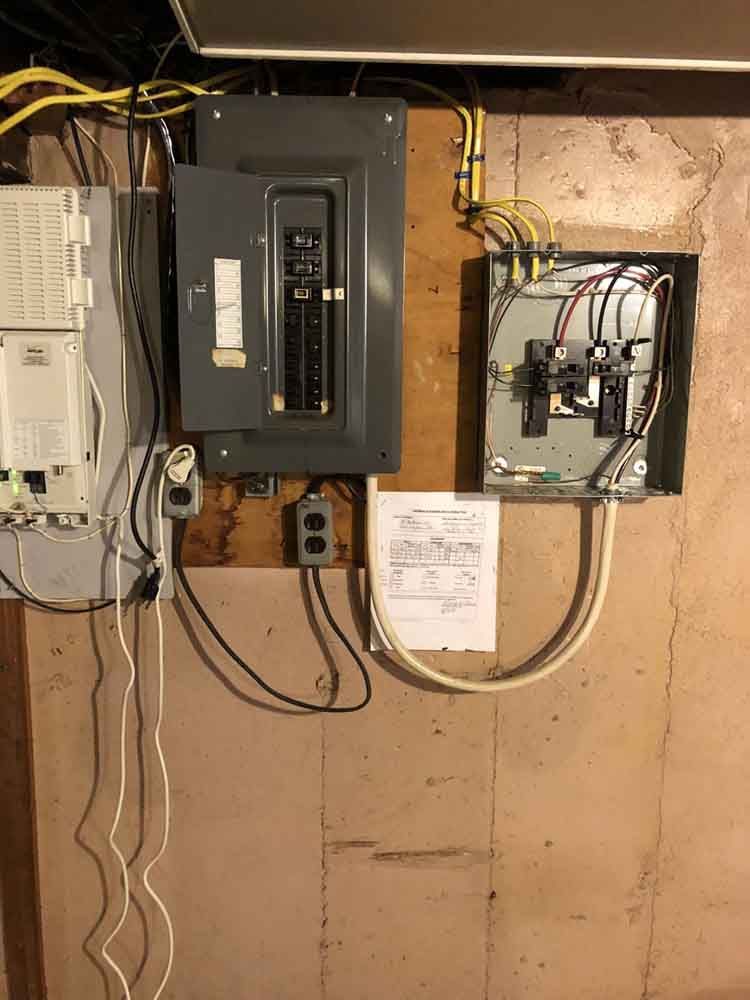 Electrical panel with breakers and wiring on a light brown wall.
