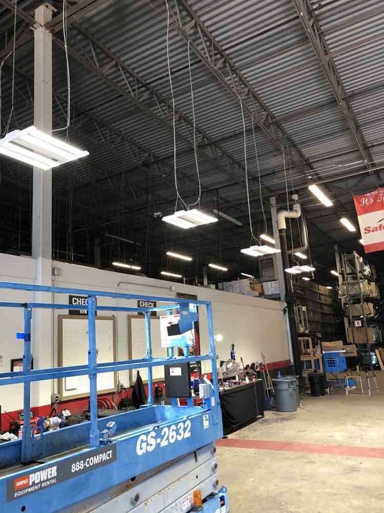 Lights suspended from a high ceiling in a store. A blue lift and other store items are visible.