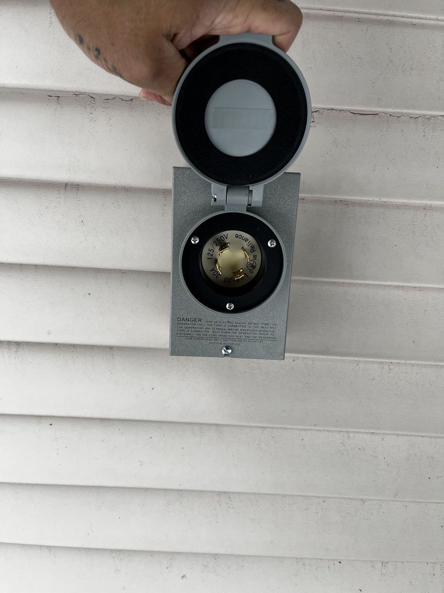 Gray outdoor electrical outlet box on white siding, held open.