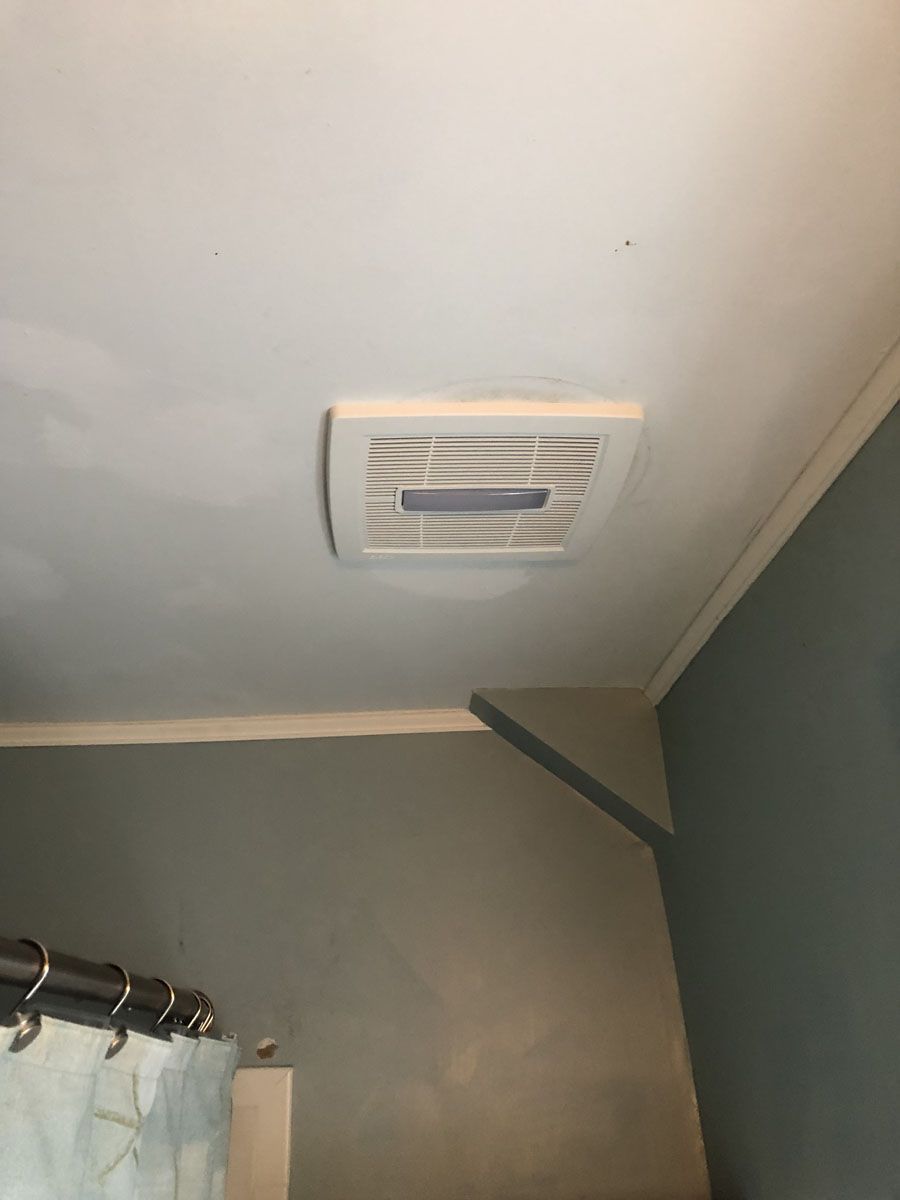 Bathroom ceiling with a white exhaust fan, a painted blue-gray wall, and shower curtain.