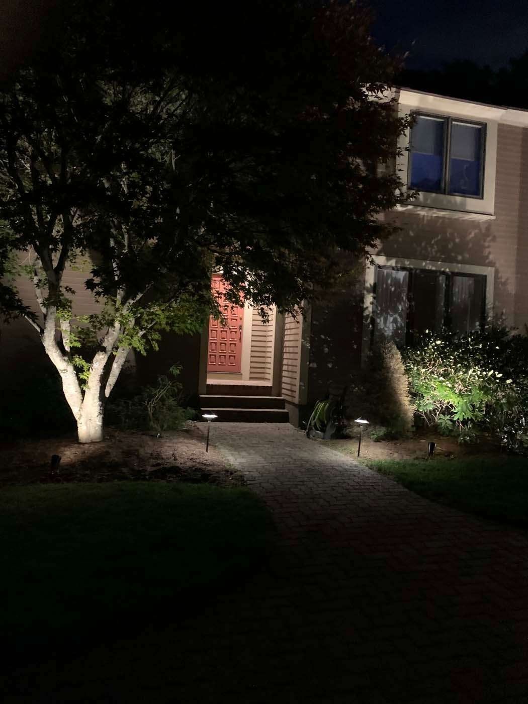 A house at night with landscape lighting illuminating the path and entrance.