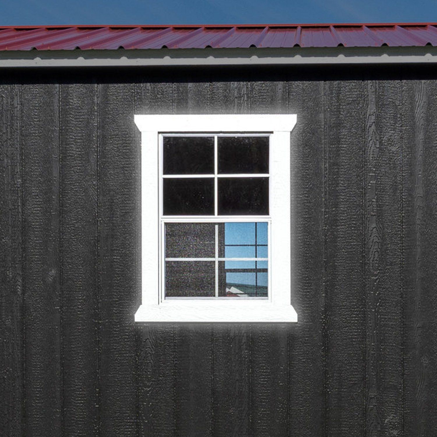 A white window is on the side of a black building.