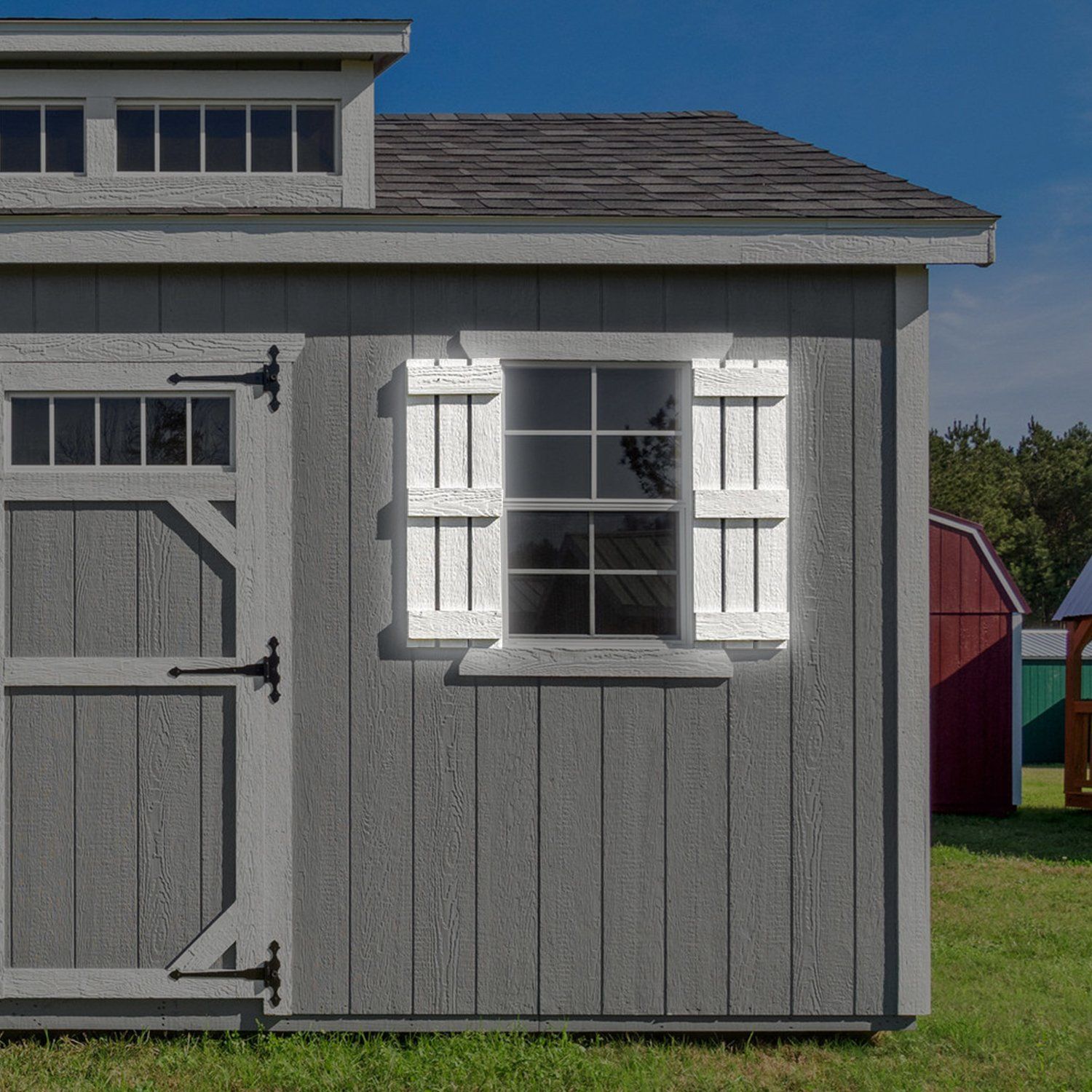 A gray shed with a window and white shutters