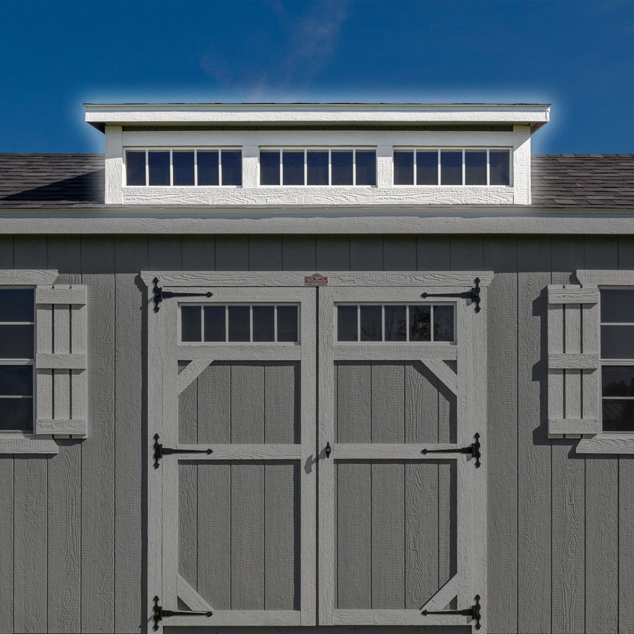 A gray shed with a white roof and shutters