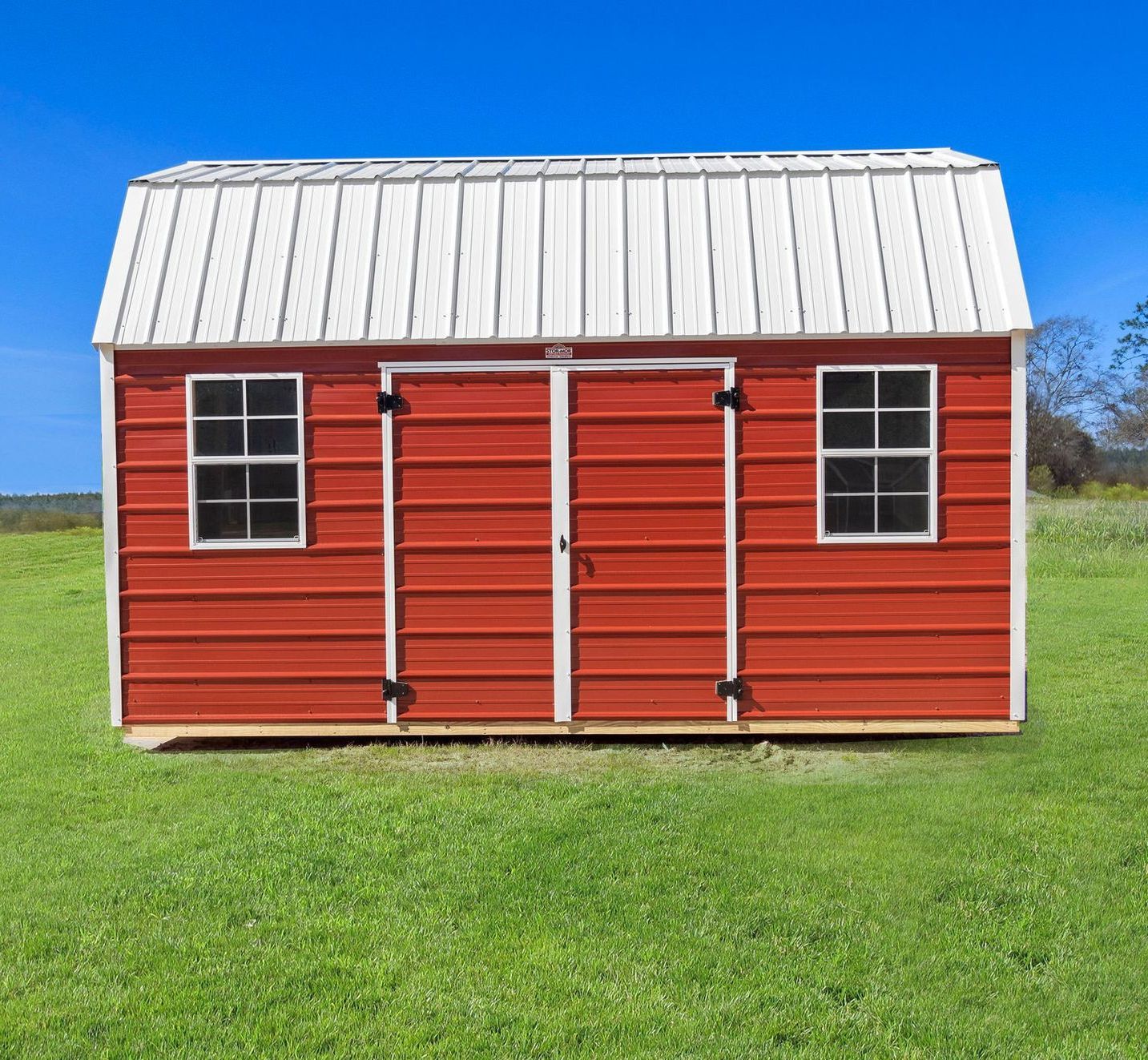 Superior Outdoor Centers metal side lofted barn A red barn with a white roof is in the middle of a grassy field.