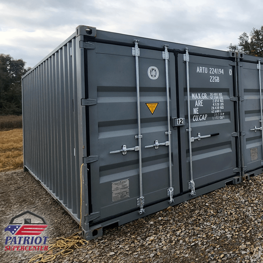 A gray shipping container is sitting on top of a gravel field.