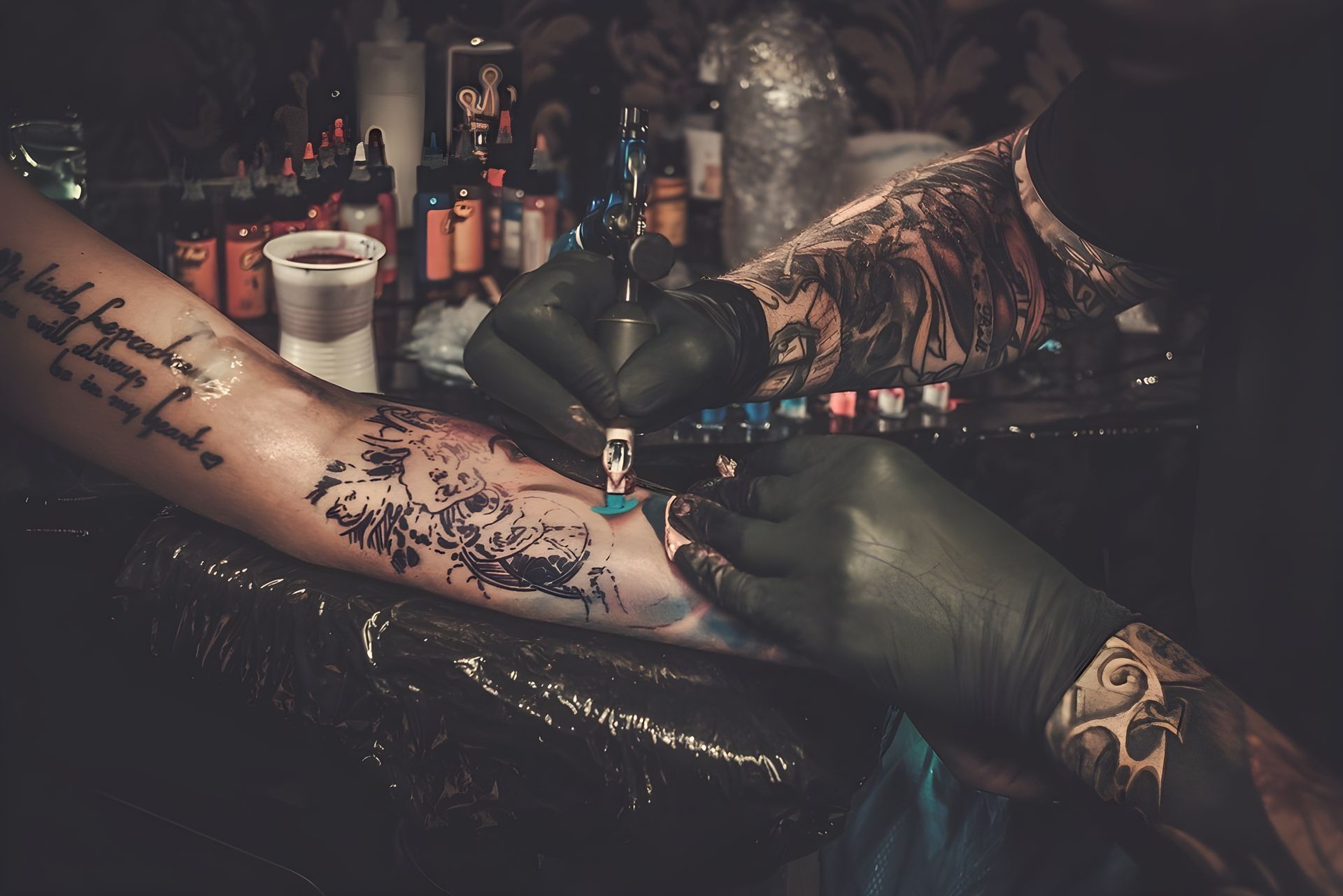 Person Getting A Tattoo On Their Arm By A Tattoo Artist, Studio Setting With Ink Bottles And Equipment — Tattoo Inc Studio in Robina, QLD