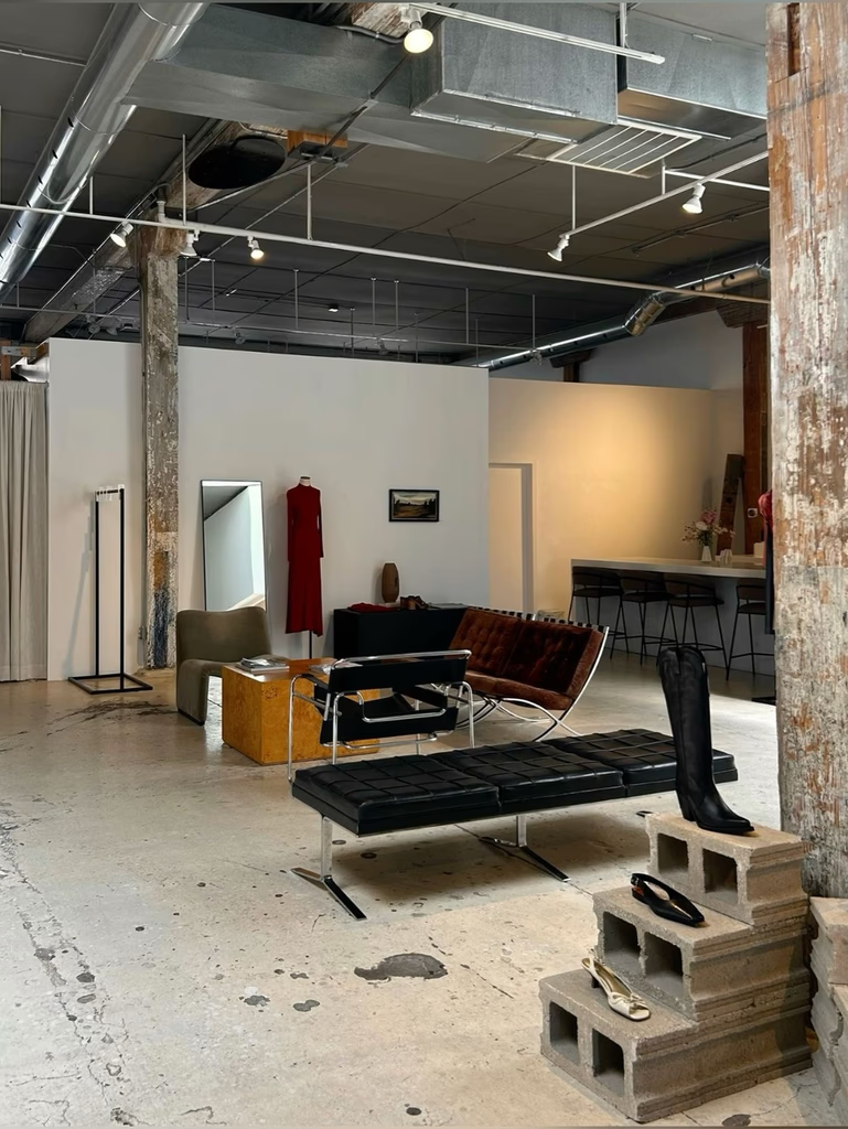 Interior of a retail space, with clothing racks, seating, and decorative elements. Exposed ceiling and concrete floors.