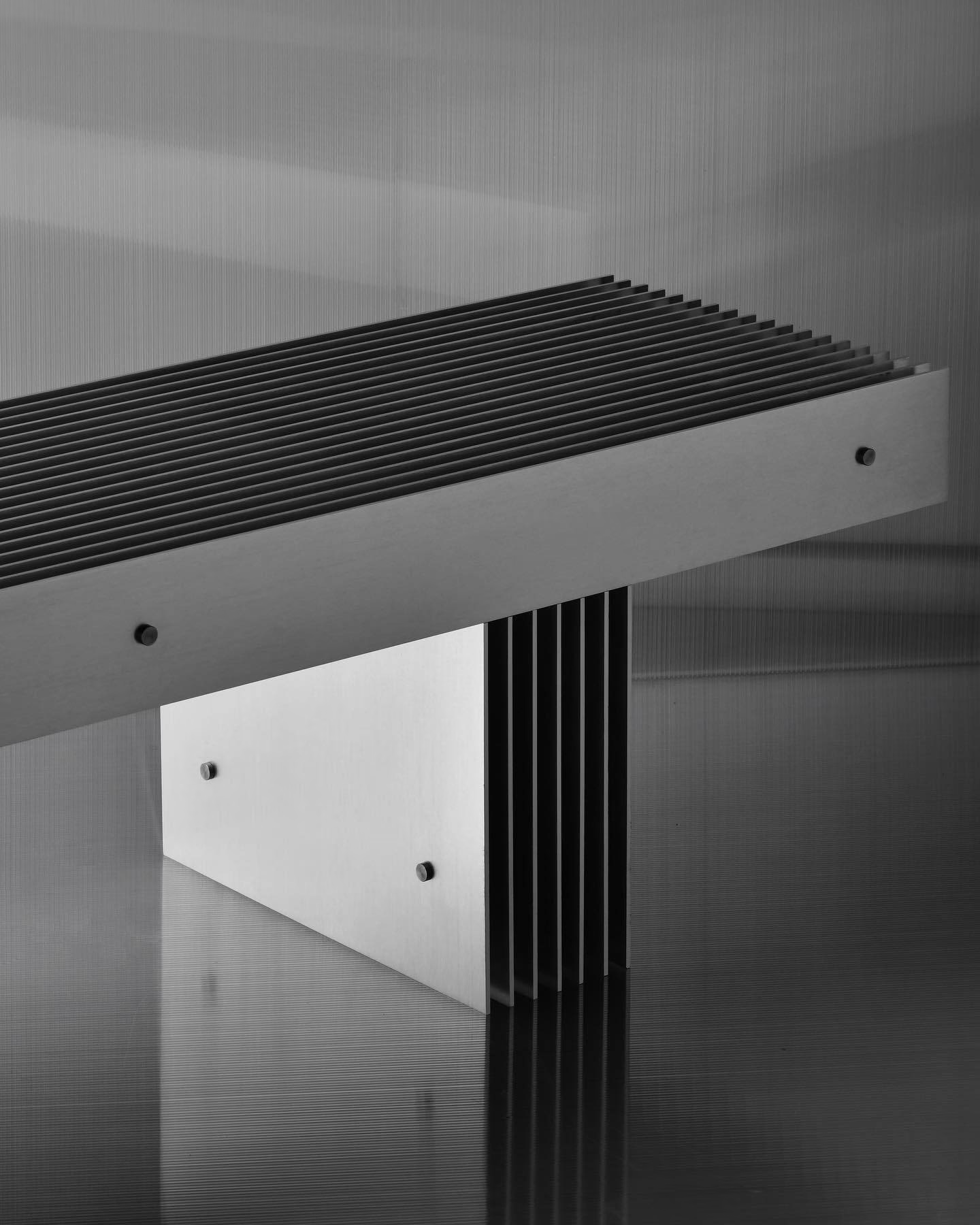 Metal bench with slatted top and finned support, reflecting light in a studio setting — Tattoo Inc Studio In Broadbeach, QLD