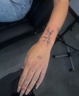 Forearm and hand with a black star tattoo, resting on a chair in an indoor setting