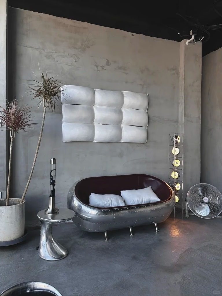 Industrial-style room with a metal loveseat, wall-mounted pillows, and minimalist decor.