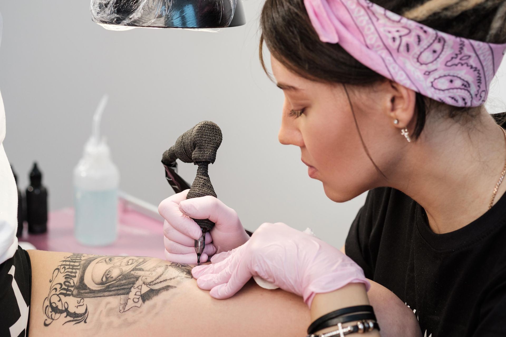 Tattoo Artist With Pink Gloves Applies Ink To A Person's Arm — Tattoo Inc Studio in Burleigh, QLD