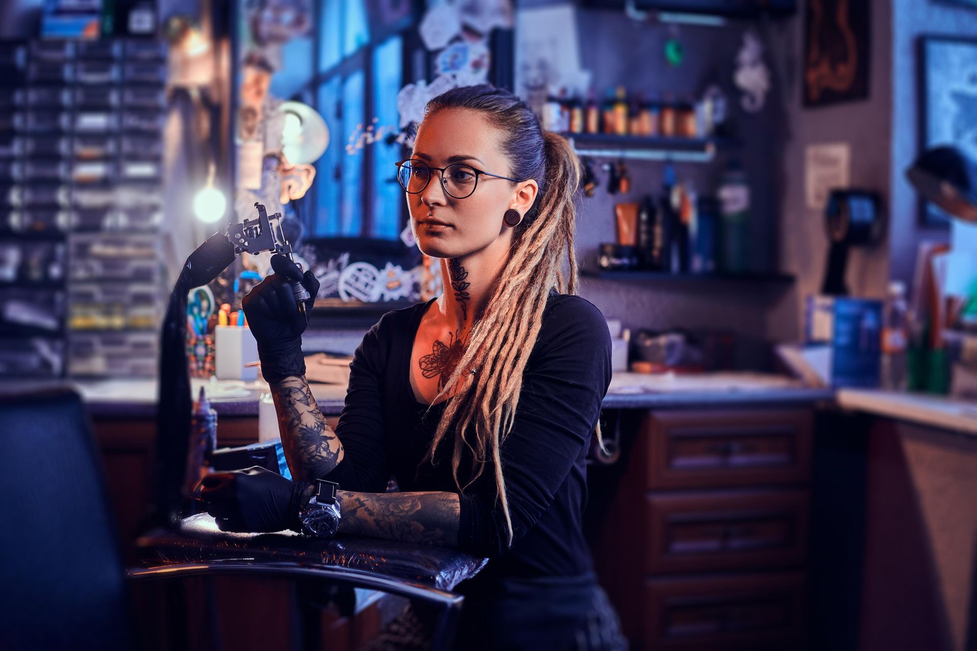Tattoo Artist With Dreadlocks And Glasses, Holding Tattoo Gun In Shop — Tattoo Inc Studio in Burleigh, QLD