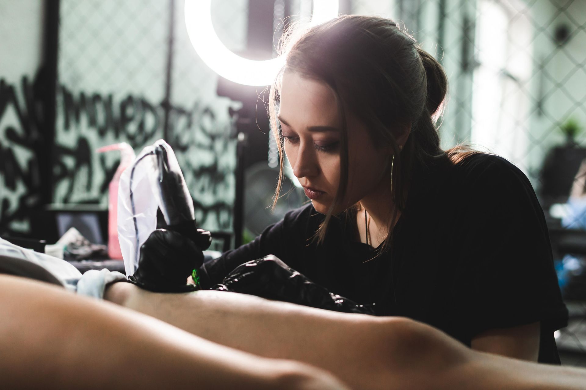 Woman Tattooing A Leg; Using A Tattoo Gun In A Studio Setting — Tattoo Inc Studio in Burleigh, QLD