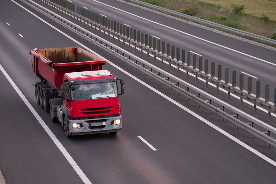 Red dump truck driving on highway.