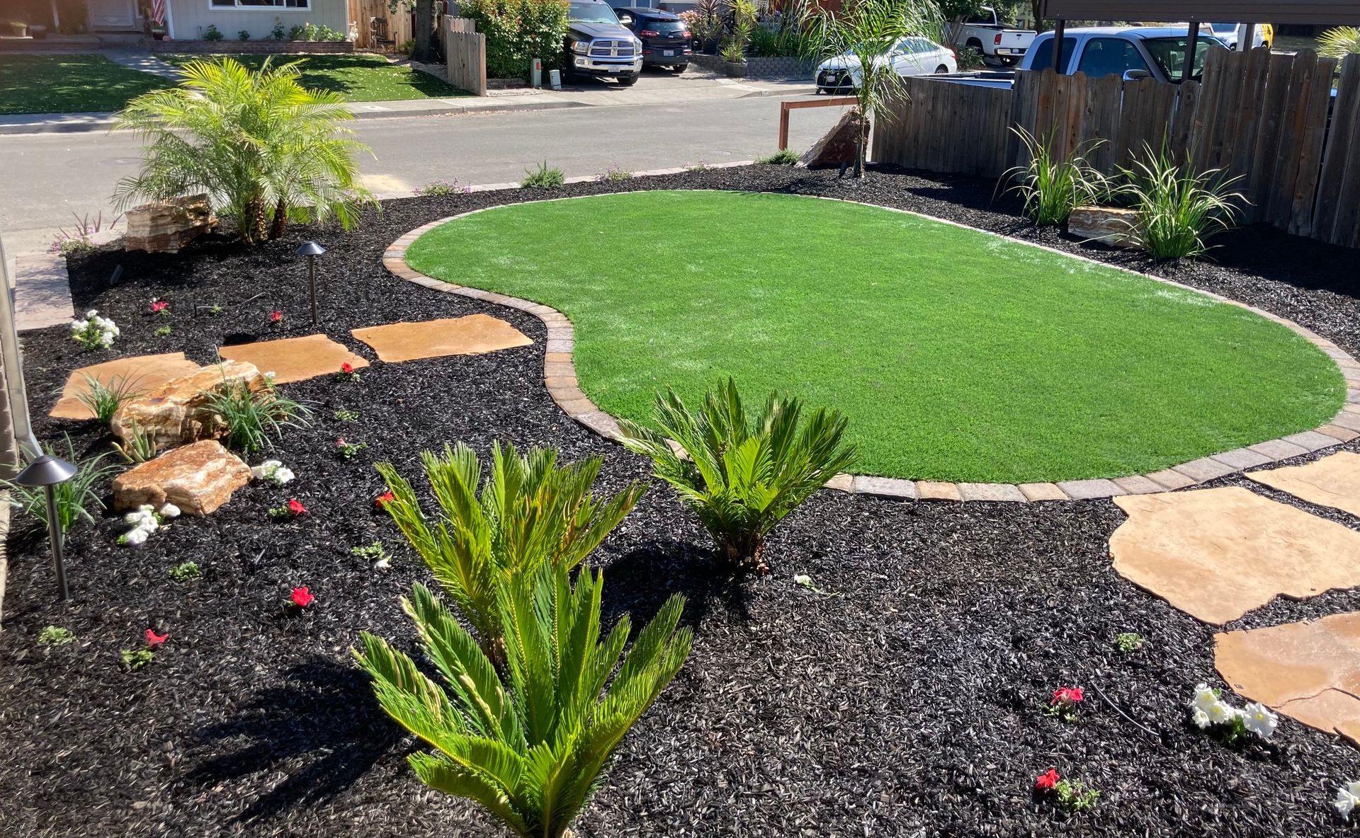 Small landscaped front yard with artificial grass, mulch, and stepping stones.