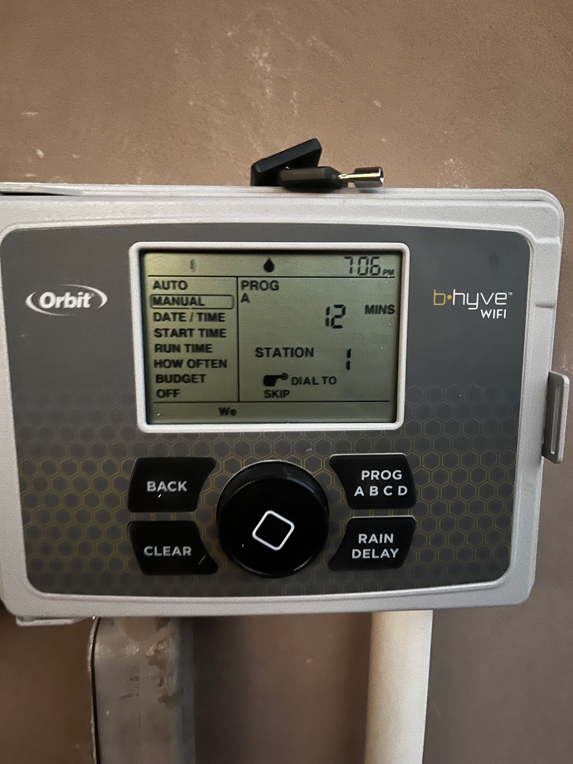 Orbit sprinkler system control panel displaying program information. Buttons and knob visible.