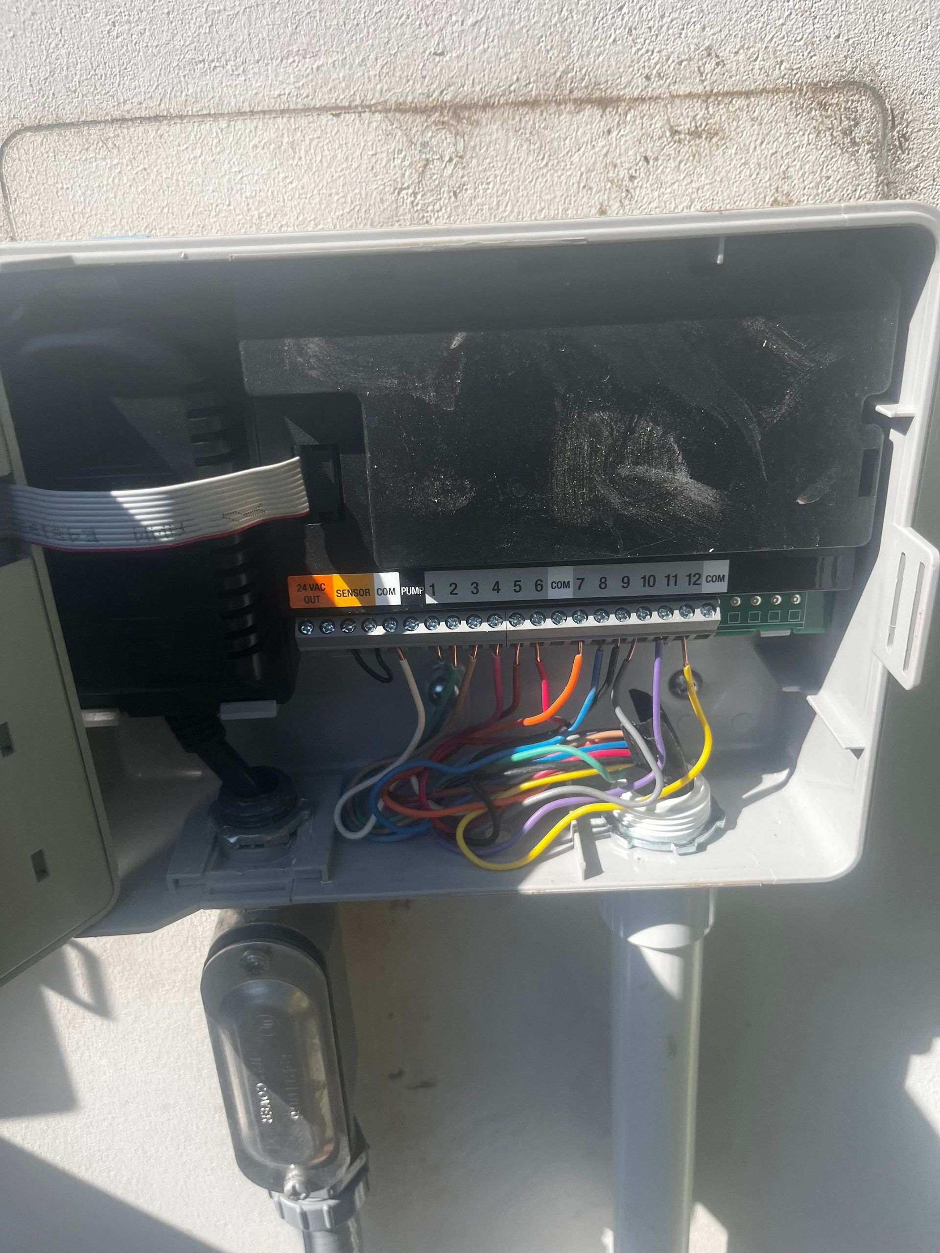 Open grey irrigation control box with colored wires connected to a circuit board.