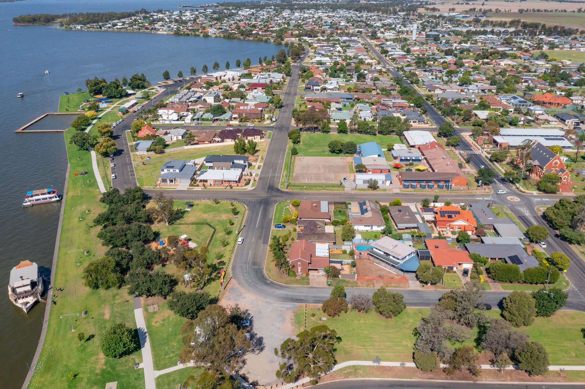 Aerial view of urban housing along a lakeside waterfront and parkland.