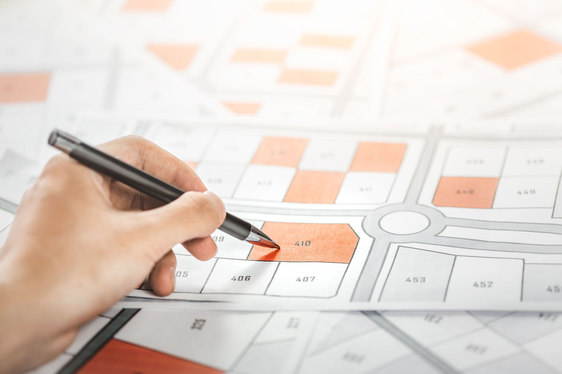 Woman holding a pencil pointing to a cadastral map to decide to buy land.