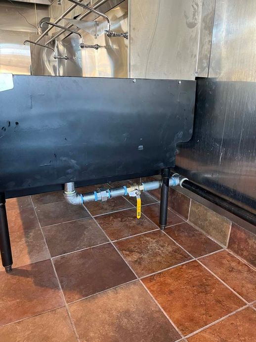 Wrench next to gas valve and yellow gas line with loose connection, on a dark surface.