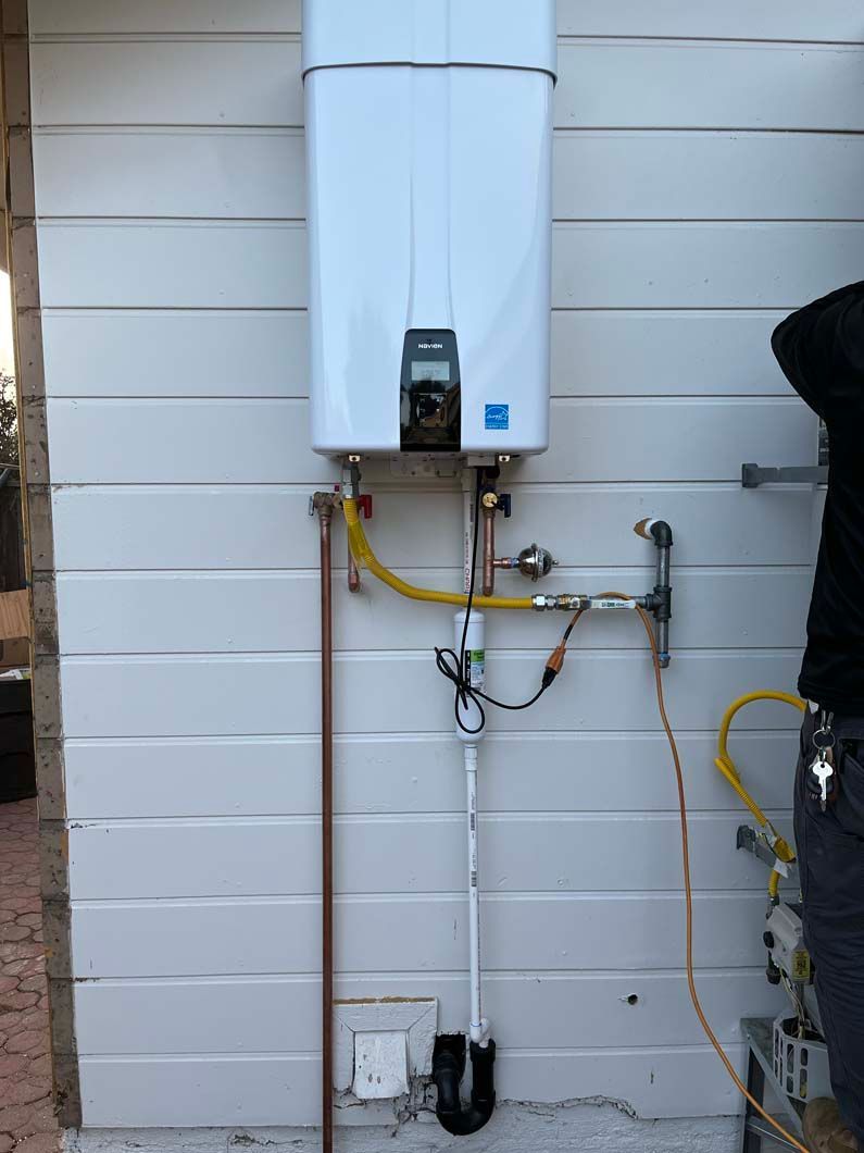 White water heater and showerhead on brown tiled wall.