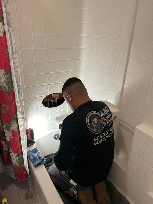 Copper pipes connected with fittings, mounted on brown tiled wall.