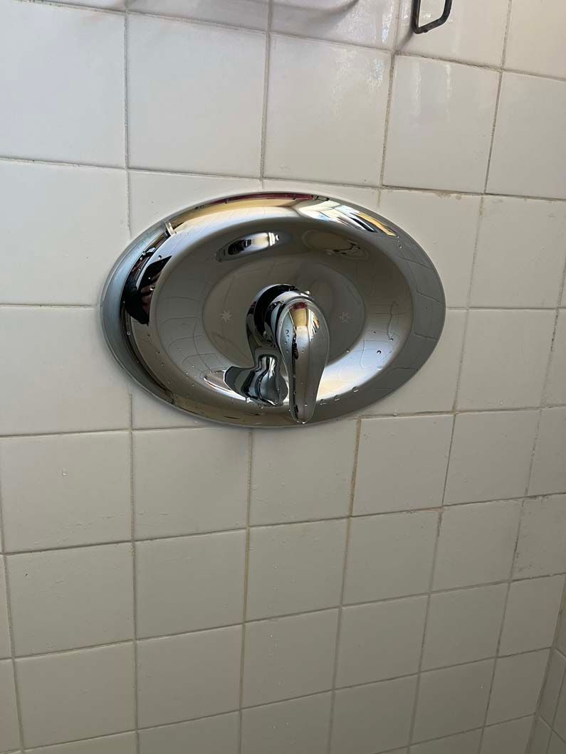 Hands of a plumber connecting pipes with a wrench in a crawl space with insulated walls.