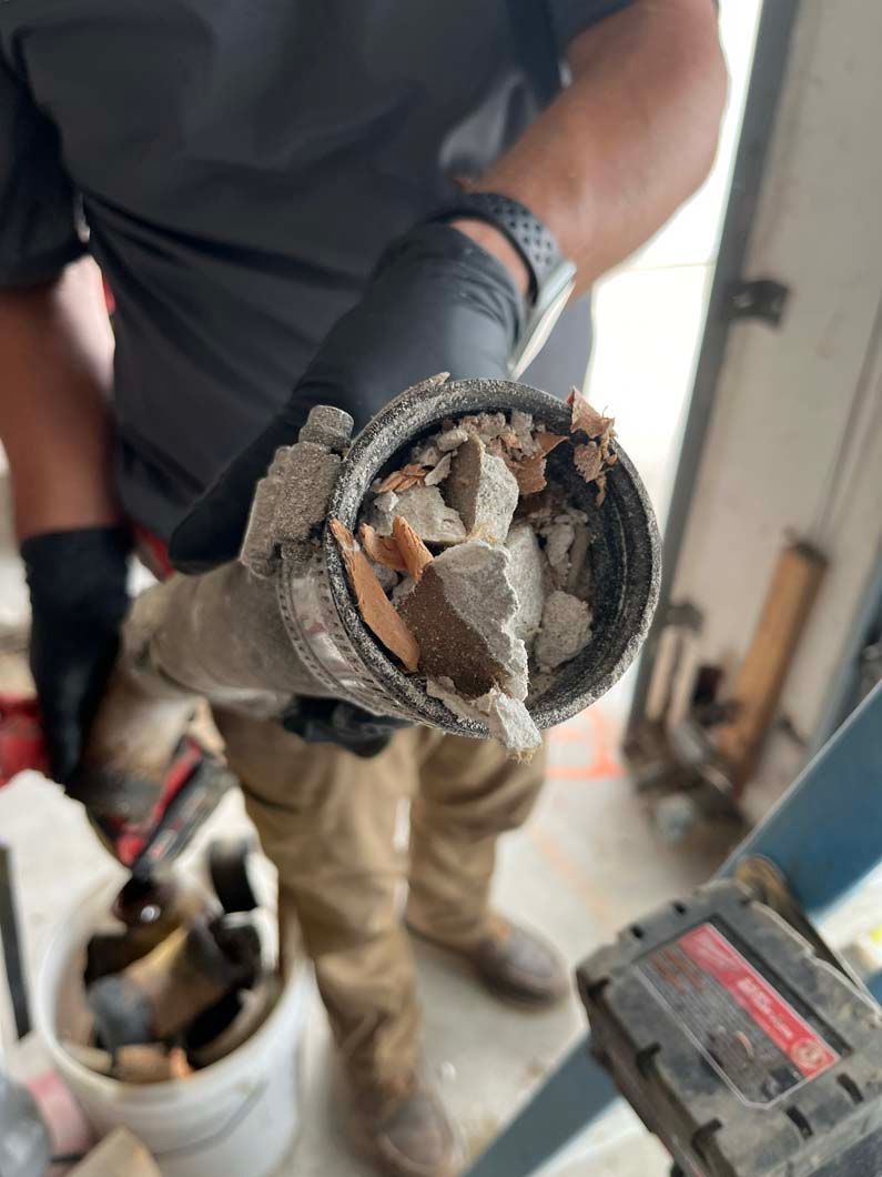 Plumber using a wrench to work on pipes under a sink.