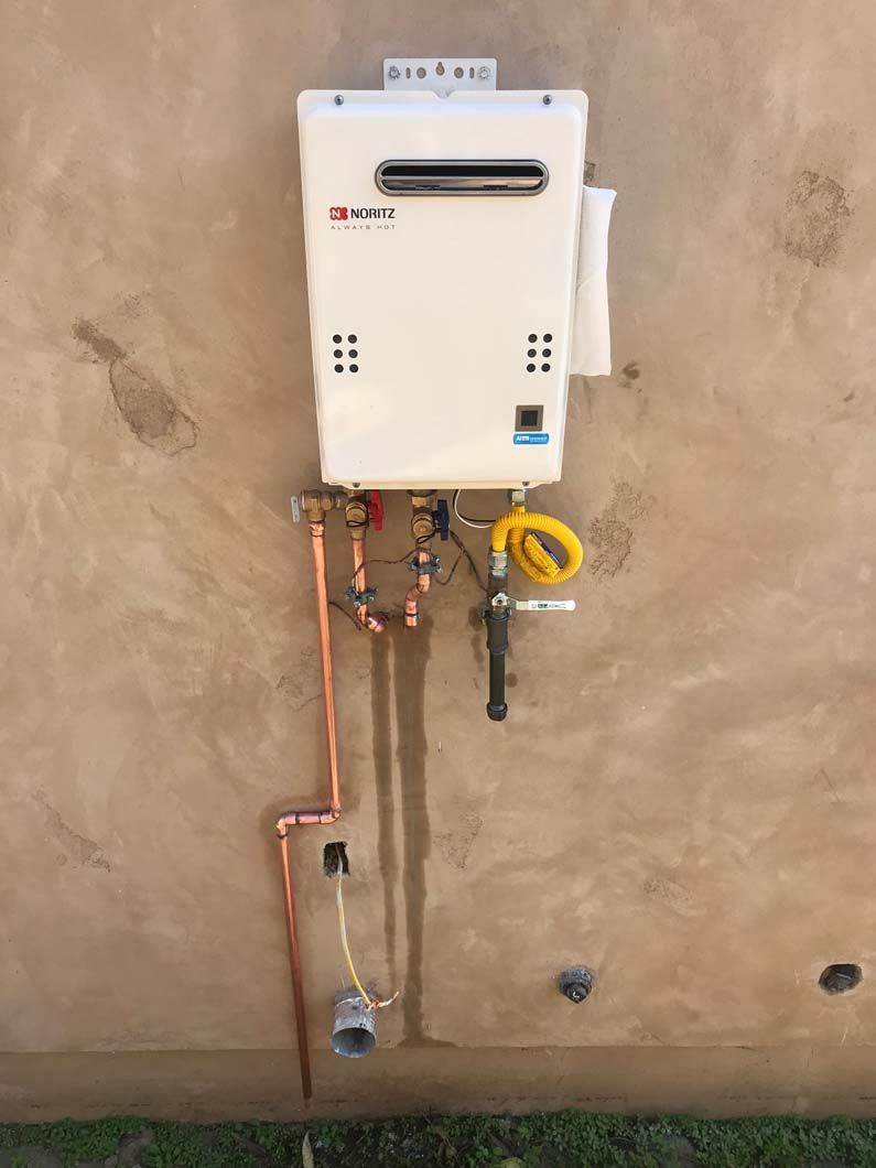 Showerhead and instant water heater mounted on a tiled wall.