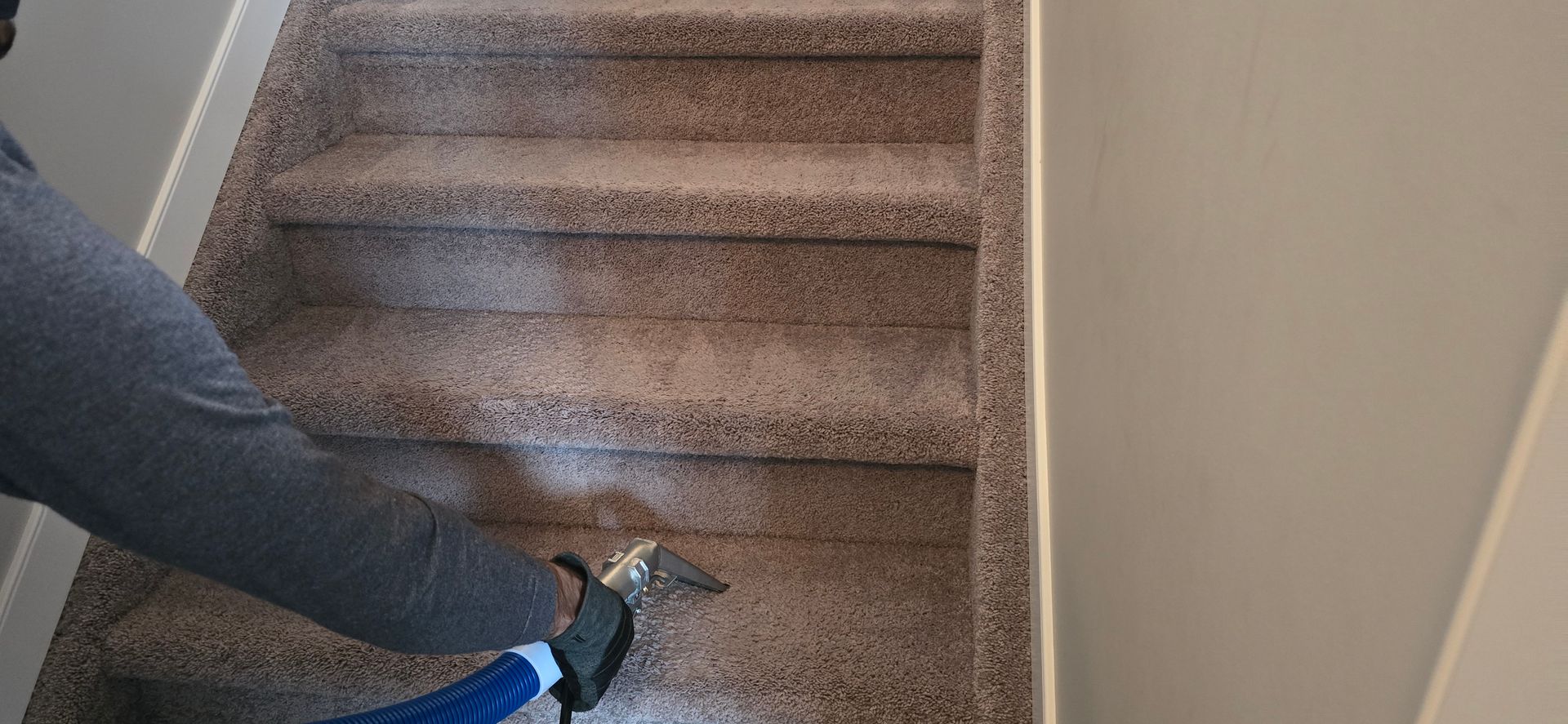 Person cleaning carpeted stairs with a vacuum.